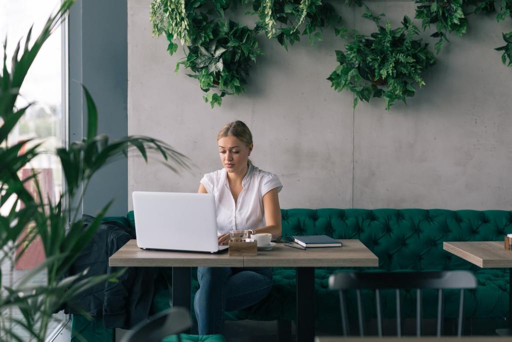 she is always on line with her business partner. Woman working on laptop in cafe bar.