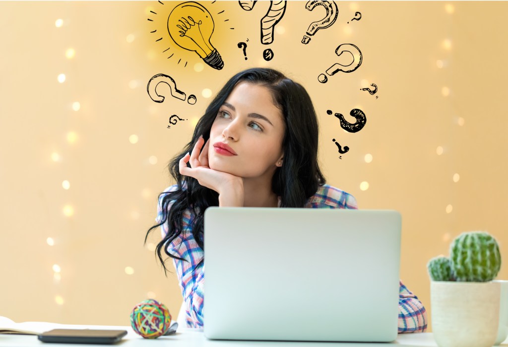 Idea light bulbs with question marks with young woman using a laptop