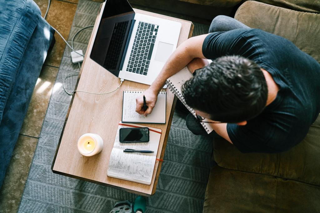 Man taking handwritten notes in front of his computer