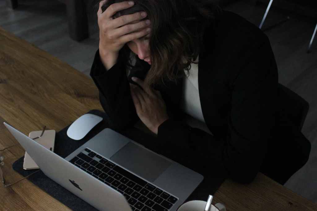 Woman with hand on her head while she stares at her computer