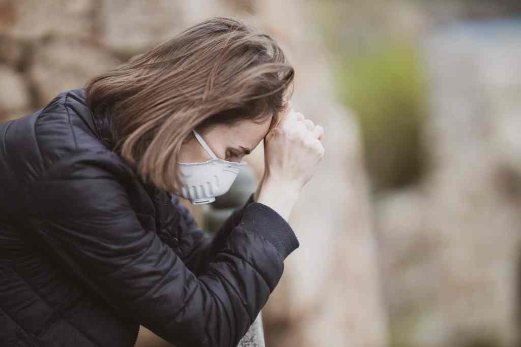 outward signs of mental fatigue - woman with mask on head in hands