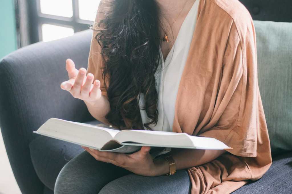 Repeat outloud what you've learned  - woman vocalizing over a textbook