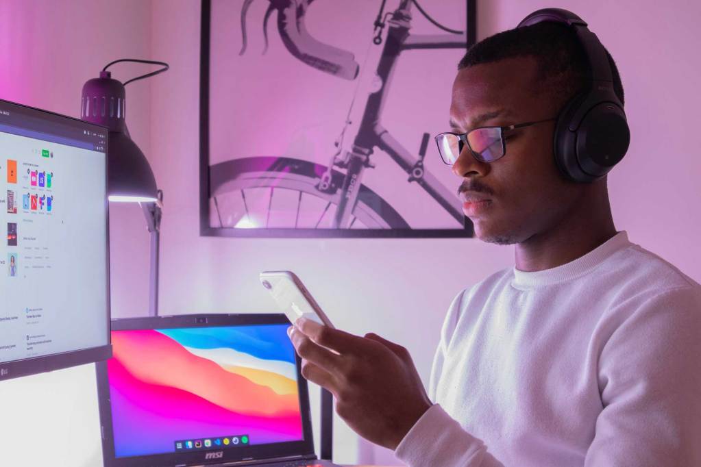 man looking at phone with mac in background