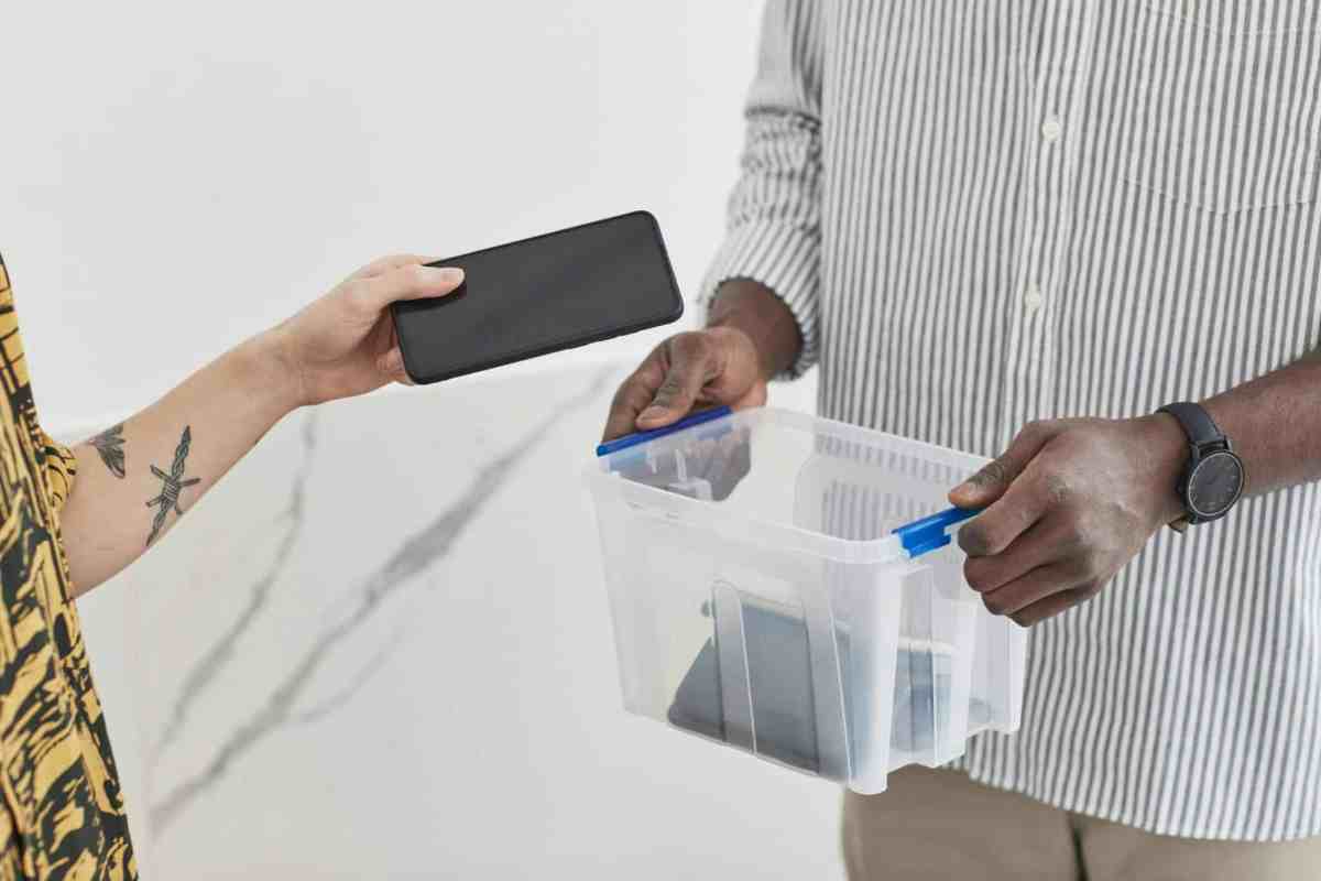 A photograph capturing a person placing their smartphone into a secured box, symbolizing a deliberate disconnect from technology. The image portrays a sense of intentionality and commitment to a digital detox, suggesting a break from constant connectivity and a focus on offline activities.