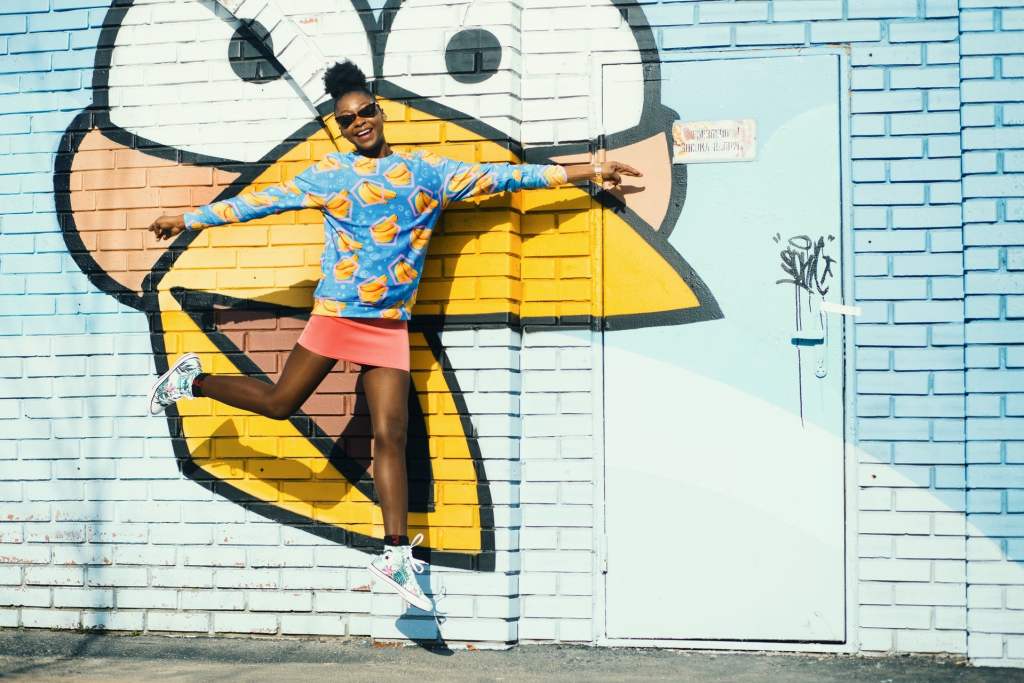 woman jumps against colorfuly painted urban wall having fun