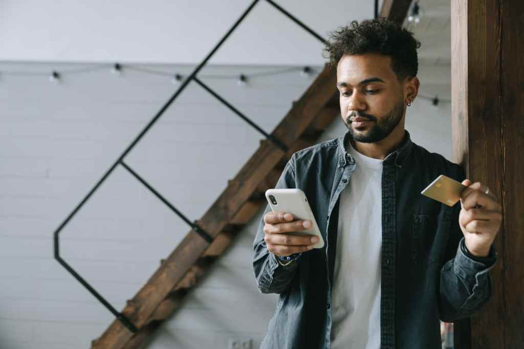 Young man online shopping with smartphone and credit card encounters analysis paralysis