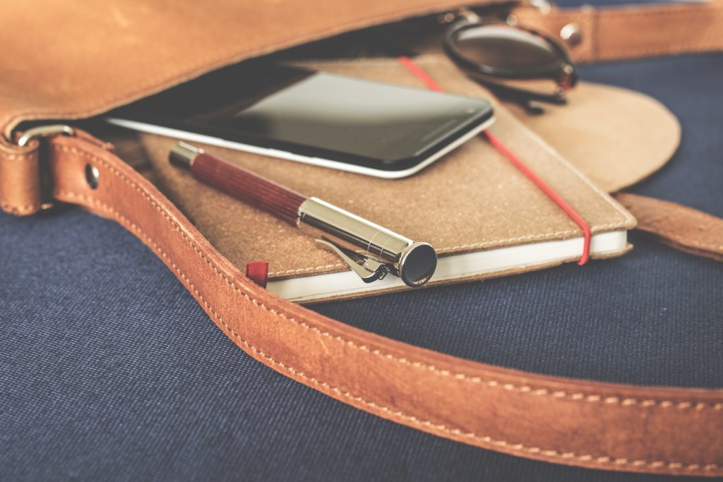 woman's purse with notebook, pen and phone