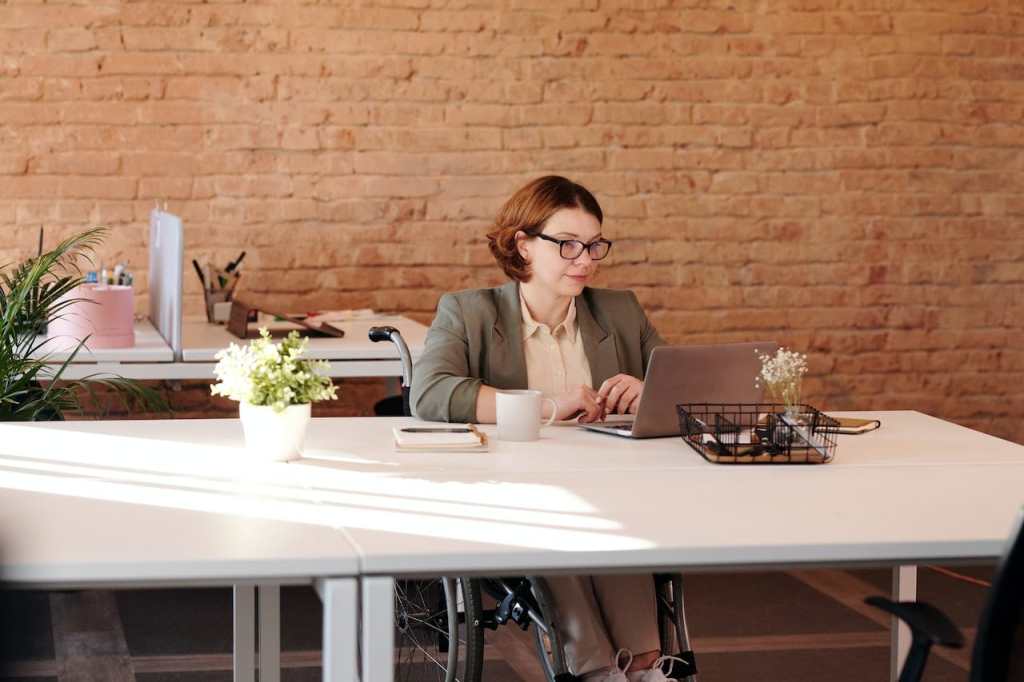 Woman in wheelchair working in office with flowers and plants