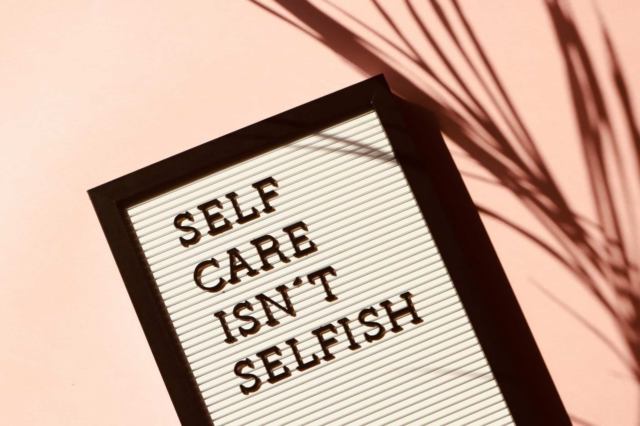 A board with the words "selfcare isn't selfish" written on it.