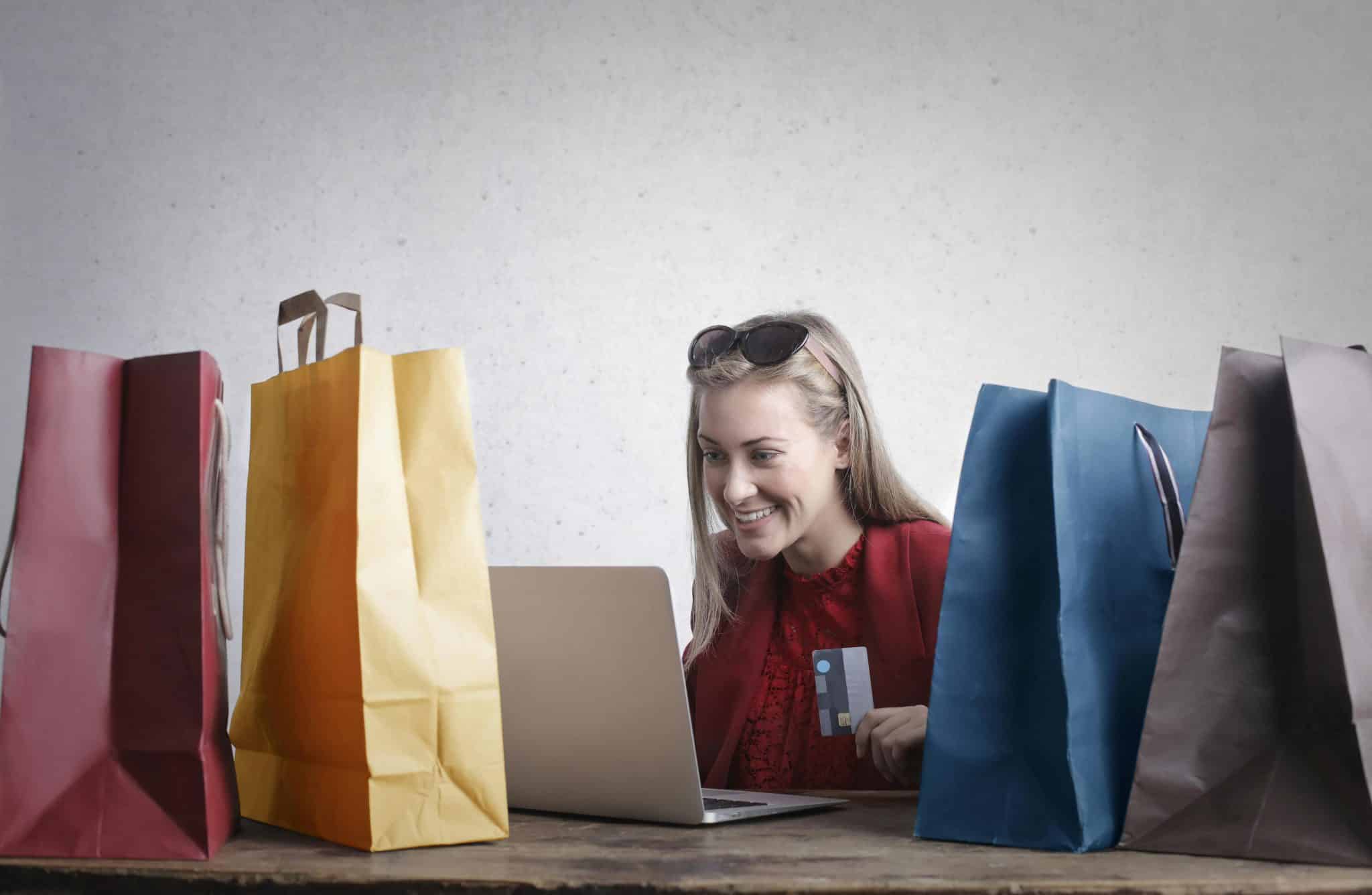 A woman engrossed in online shopping, surrounded by numerous bags, neglecting her surroundings.