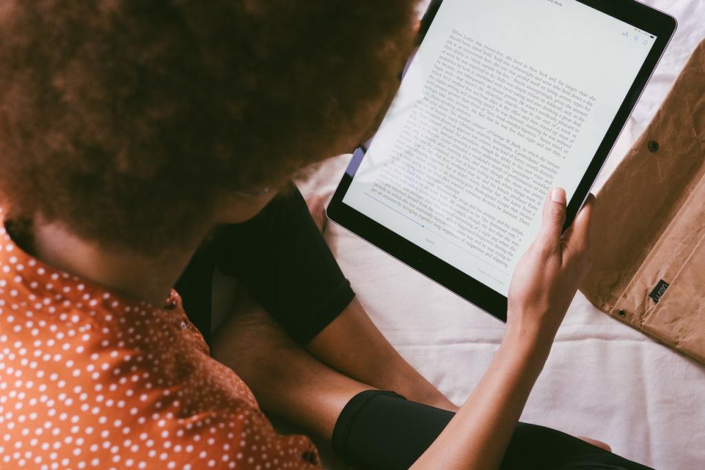 Black woman studying on an iPad tablet reading