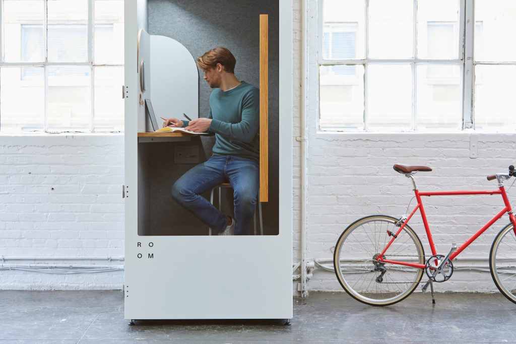 focus guide - Man working undistracted in a telephone box with a desk