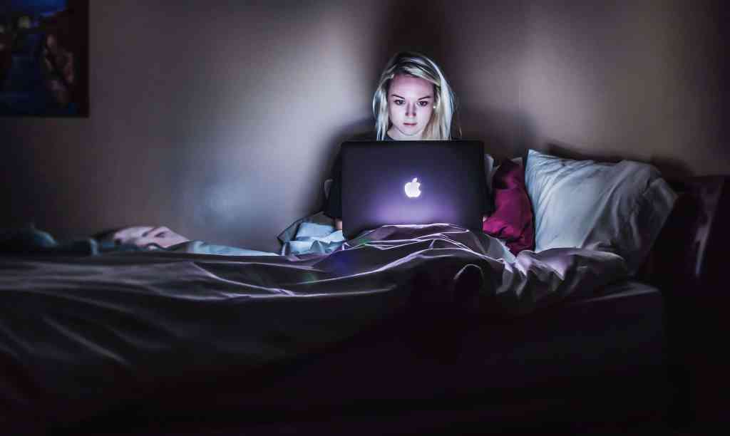 Why do people hate social media? Young women sitting in dark on her laptop